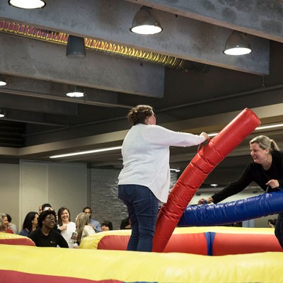 Two Fossil Group employees play jousting game at annual spring fest
