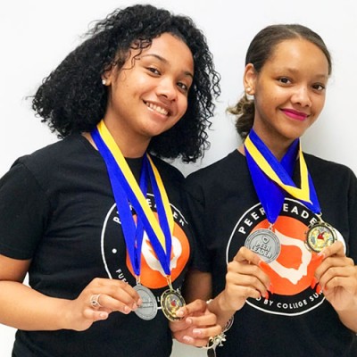 Two Peer Leaders with Fossil Foundation partner org PeerForward pose with medals