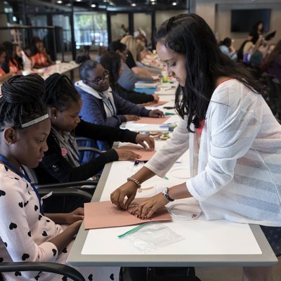 Hari Bhimaraju helps a group of students at a STEM workshop at an IDG event at Fossil Group in Texas